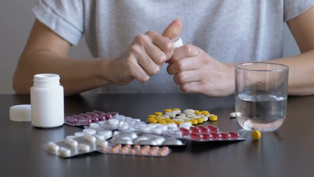Desperate woman attempts to commit suicide with pills. When provoking suicide, women's hands shake out all the pills from the vial. Girl holds a handful of pills