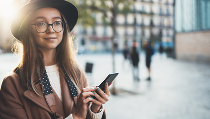 Traveler woman in hat holding mobile phone. Close up technology smartphone online connect. Girl tourist in glasses using gadget cellphone in sun flare city. Digital internet lifestyle mockup
