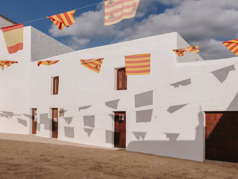 Flags of Ibiza hanging on old town with white houses