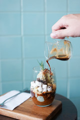 Affogato, Italian dessert. A hand pouring down hot coffee (espresso shot) on the mint ice cream and marshmallow. Soft focus.