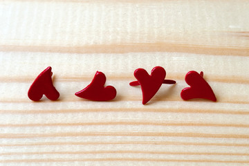 Four metallic red hearts on a wooden background