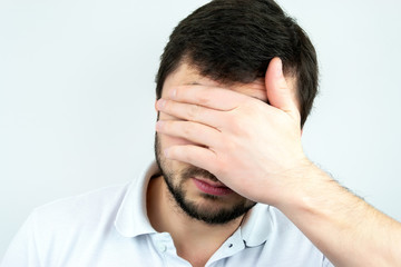 Closeup portrait of a bearded man holding palm over his face