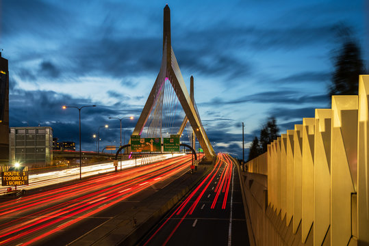 Highway suspension bridge with light trails left by passing vehicles at dusk. Boston MA, USA.