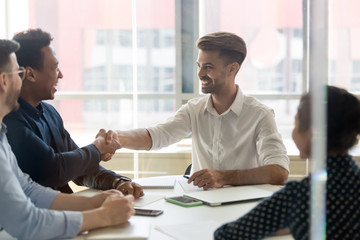 Young positive businessmen handshaking greeting each other