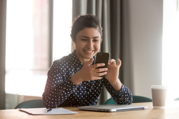 Smiling happy indian woman using smartphone or video calling