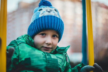 little boy swinging on a swing on a winter day