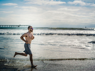 Running man along the Pacific Ocean in Ocean Beach, San Diego, California, USA.