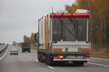 Heavy low-frame truck with semi-trailer trawl transport industrial equipment on a two-lane suburban...