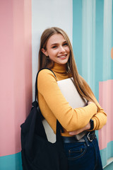 Fototapeta Pretty joyful casual student girl with laptop happily looking in camera over colorful background outdoor obraz