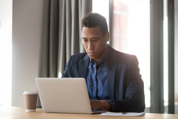 Serious african american employee working with computer at office