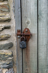 Old combination padlock with rusty lock on a wooden door