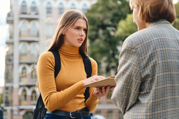 Upset student girl frustratingly discussing homework with friend during study break outdoor