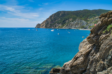 Fototapeta na wymiar In the mountains of Liguria by the sea. View of the sea bay from a hiking trail, boats and yachts in the parking lot, Italy