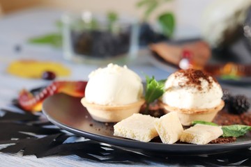 Halloween food, autumn leaves and dessert with chocolate, ice cream and jelly worms on a wooden table