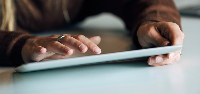 Close-up of young businesswoman's hands using digital tablet in office