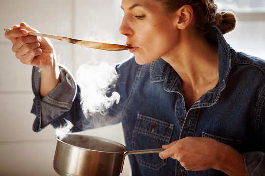 Woman tasting food while cooking in kitchen