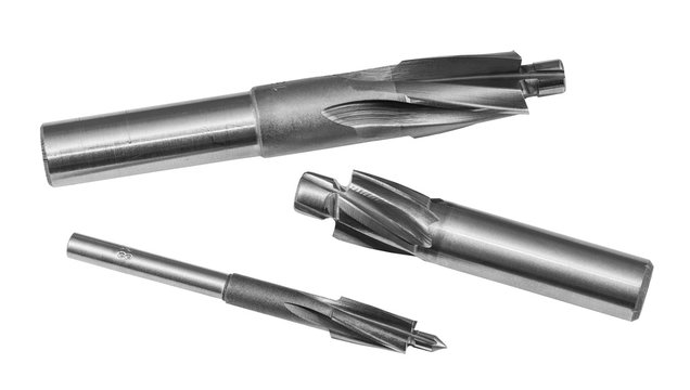 Three steel cylindrical counterbores isolated on white background. Sharp cutting tools set for drilling counterbored coaxial holes. Detail of spiral fluted cutters. Metal equipment for chip machining.