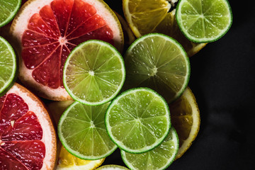 Slices of pink Star Ruby grapefruit and green lime on black background