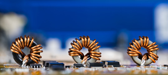 Panoramic electrotechnical background. Toroidal inductors with beautiful copper wire winding....