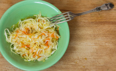sauerkraut in a plate with a fork on a wooden background