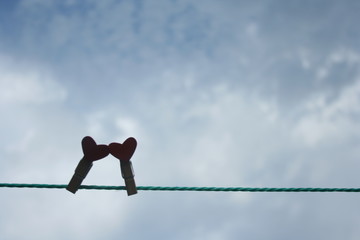 Heart  on wooden pegs on a white blue sky  background. Valentines's day concept.