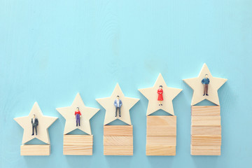 photo of 5 star symbols with people figures over wooden table ,human resources and management...
