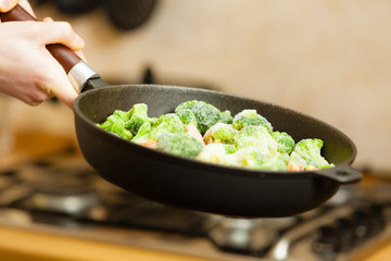 Woman cooking stir fry frozen vegetable on pan