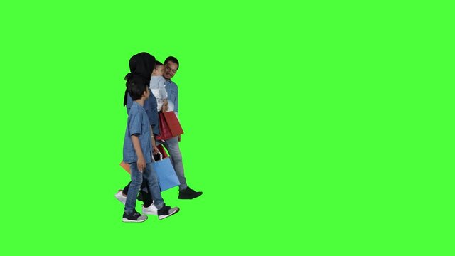 Happy family walking in the studio while carrying shopping bags. Shot in 4k resolution with green screen background