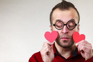 Sad man holding two red hearts.