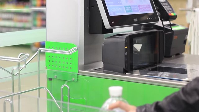 Customer hand scanning barcode of food under price scanner machine installed on wall. Convenient solution in hypermarket.