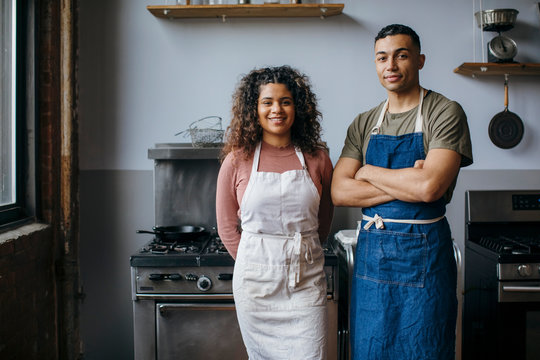 Portrait of confident smiling students standing against wall in kitchen