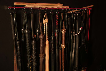 Whips for BDSM on a dark background. Accessory for sexual games. - obrazy, fototapety, plakaty