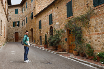 Fototapeta na wymiar Young traveler walking the streets of San Quirico in Tuscany, Italy