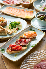Bruschetta with beef, tomatoes and salmon.. Variety of dishes on the table. Various snacks and antipasti on the table. Restaurant menu. Italian cuisine