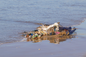 Clothes, plastic and household waste rubbish washed up from the Atlantic Ocean on sand beach at Agadir, Morocco