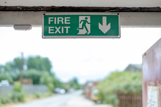 Shallow focus, isolated image of a green Fire Exit sign seen attached an internal factory door frame, leading to the outside of the factory for fire emergencies.