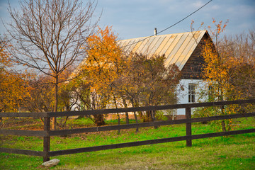 Rustic house with fence in autumn