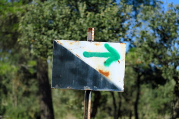 Panneau en fer noir et blanc avec flèche verte peinte dirigée vers la droite.