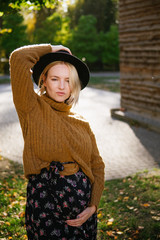 Boho style young pregnant woman in hat and orange sweater