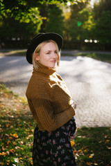 Boho style young pregnant woman in hat and orange sweater