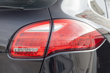Rear taillamp view of car in black color after cleaning before sale in a sunny summer day