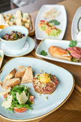 Beef tartar in the restaurant. Variety of dishes on the table. Various snacks and antipasti on the table. Restaurant menu. Italian cuisine