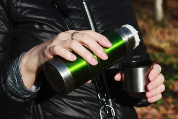 Fototapeta premium Woman pours tea from a thermos in the woods