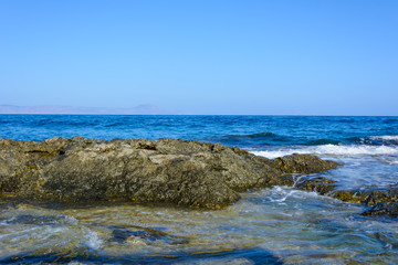 Fototapeta na wymiar part of the rocky coast and calm sea. silhouette of mountains on the horizon