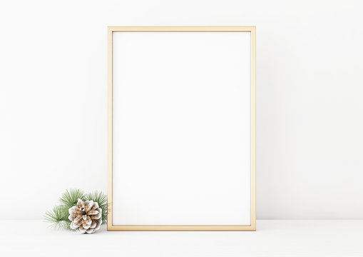 Vertical christmas poster mockup with golden frame and pine cone on white wall background. 3D rendering, illustration.