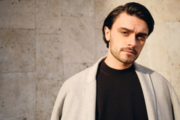 Portrait of young handsome brunette man intently looking in camera outdoor