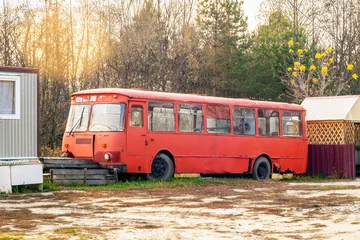 Foto op Plexiglas een oude verlaten bus in de open lucht staat tegen de achtergrond van een dennenbos. Rode pittige zeldzame bus in het bos © Firuza