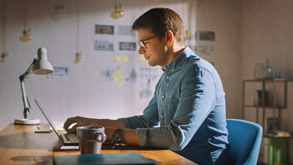 Professional Creative Man Sitting at His Desk in Home Office Studio Working on a Laptop. Man working with Data and Analyzing Statistics.