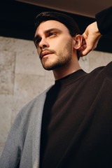 Portrait of young stylish man with coat on shoulder dreamily looking away outdoor