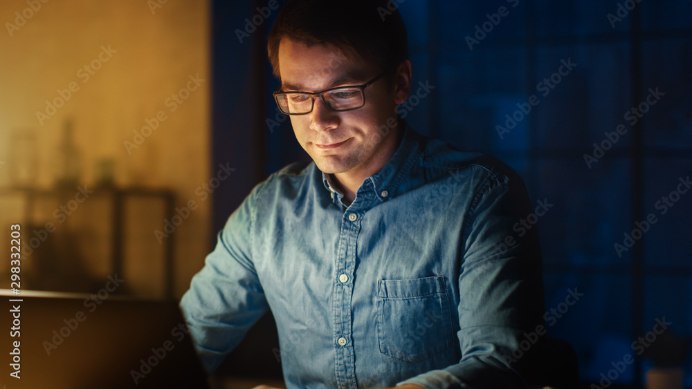 Poster professional man sitting at his desk in office studio working on a laptop in the evening. man workin